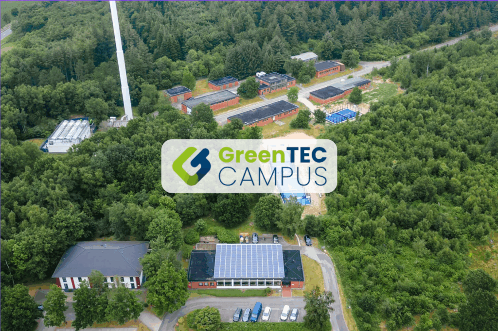 Luftaufnahme des GreenTEC Campus in Enge-Sande, eingebettet in eine grüne Waldlandschaft, mit sichtbaren Solaranlagen und modernen Gebäuden – ein Reallabor für Nachhaltigkeit und Zukunftstechnologien.