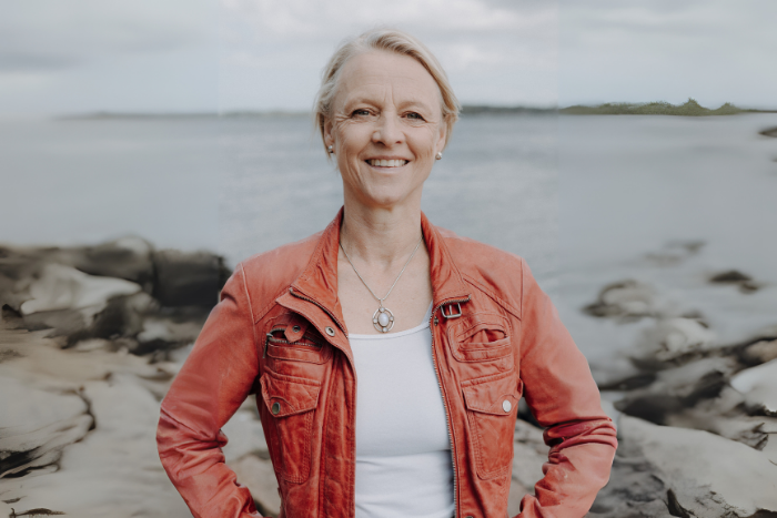 Dr. Tenna Dahl stellt sich lächelnd vor. Im Hintergrund sieht man das Meer und die Küste.